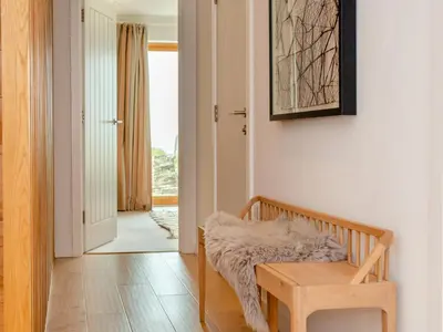 a room with a bench and a table and a hallway at 3 Karn Havos in Mawgan Porth
