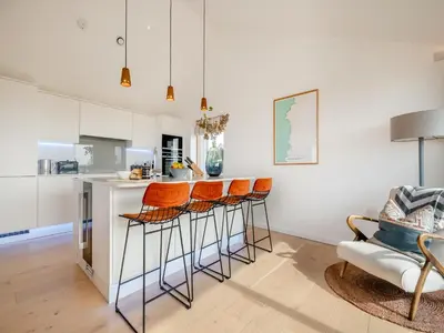 a kitchen with orange bar stools and a counter at 3 Karn Havos in Mawgan Porth