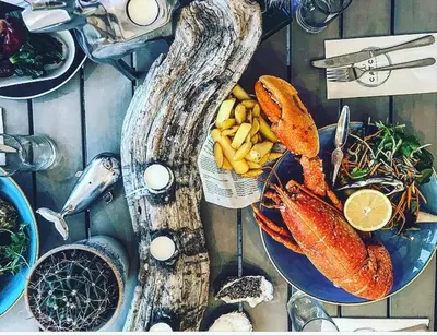 a plate of food with lobsters on a table at Fabulous Beach Pad Just 20 Paces From The Sea in Mawgan Porth