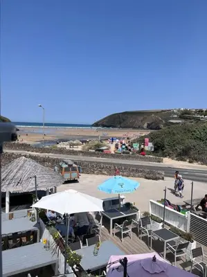 a patio with tables and umbrellas and a beach at Fabulous Beach Pad Just 20 Paces From The Sea in Mawgan Porth