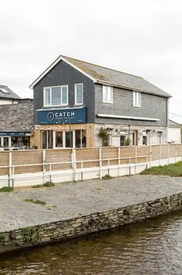 a building next to a body of water at Fabulous Beach Pad Just 20 Paces From The Sea in Mawgan Porth