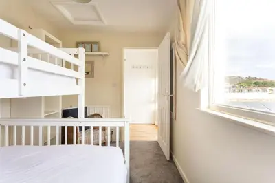 a bedroom with a white bunk bed and a window at Fabulous Beach Pad Just 20 Paces From The Sea in Mawgan Porth