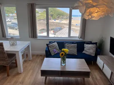 a living room with a blue couch and a table at Fabulous Beach Pad Just 20 Paces From The Sea in Mawgan Porth