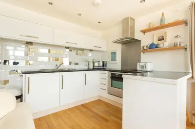a kitchen with white cabinets and a stove top oven at Fabulous Beach Pad Just 20 Paces From The Sea in Mawgan Porth