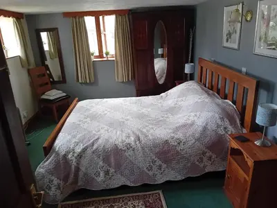 a bedroom with a bed with a white comforter at Robins Nest in Liskeard