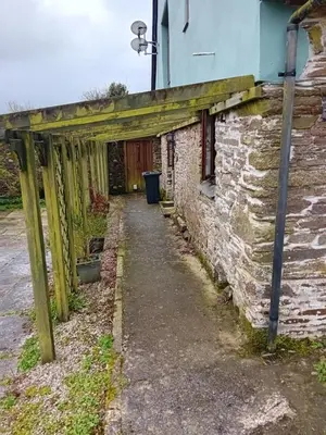 a wooden pergola attached to a brick building at Robins Nest in Liskeard