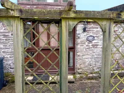 a gate in front of a building with a red door at Robins Nest in Liskeard