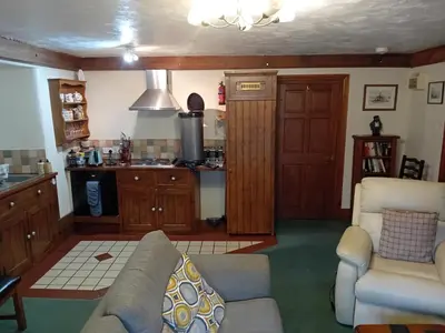 a living room with a couch and a kitchen at Robins Nest in Liskeard
