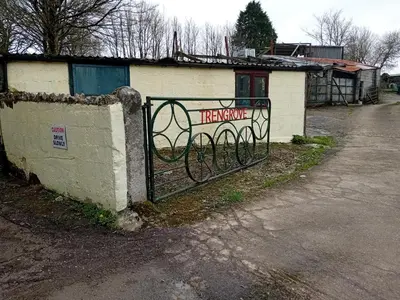 a gate with a sign on it next to a building at Robins Nest in Liskeard