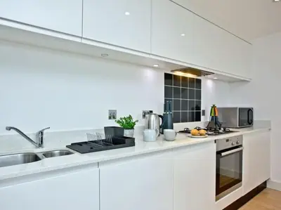 a white kitchen with a sink and a stove at 15 Ocean Gate Newquay in Crantock