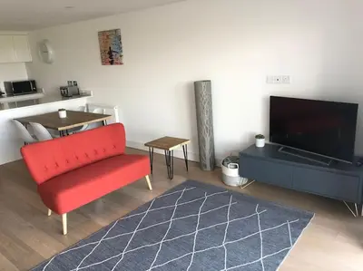 a living room with a red chair and a television at 15 Ocean Gate Newquay in Crantock