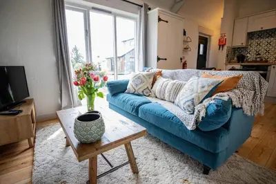 a living room with a blue couch and a table at Treworgie Barton Cottages - Chappell in Bude
