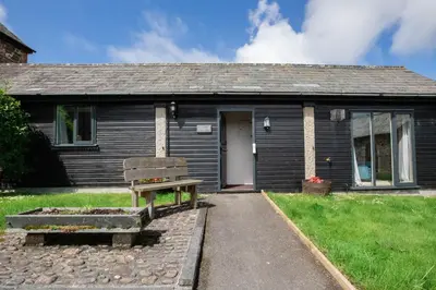 a small house with a bench in front of it at Treworgie Barton Cottages - Chappell in Bude