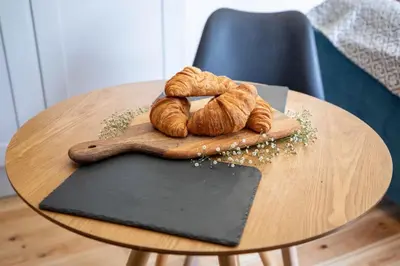 a table with a wooden spoon and croissants on it at Treworgie Barton Cottages - Chappell in Bude