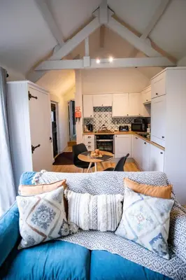 a living room with a blue couch and a kitchen at Treworgie Barton Cottages - Chappell in Bude