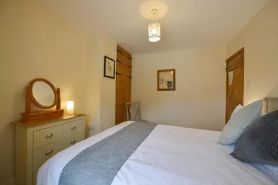 a bedroom with a bed with a mirror and a dresser at Swallow Cottage in Helston