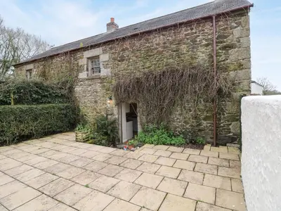 an old brick building with a patio in front of it at Swallow Cottage in Helston