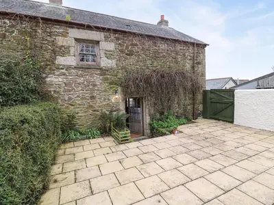 a brick building with a gate and a patio at Swallow Cottage in Helston