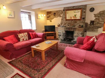 a living room with two red couches and a fireplace at Swallow Cottage in Helston