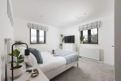 a white bedroom with a bed and a tv at Atlantic Point, Porthleven - Free WiFi & Parking - Coffee Machine - Close to Harbour & Town in Porthleven