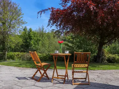 two chairs and a table with a vase of flowers at Lakeside in Falmouth