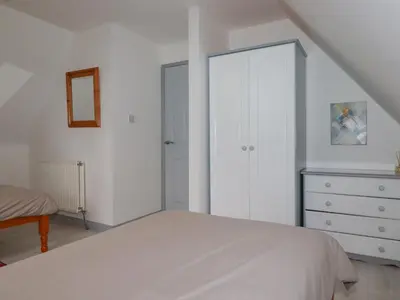 a white bedroom with a bed and a dresser at Rainbow Lodge in Bodmin