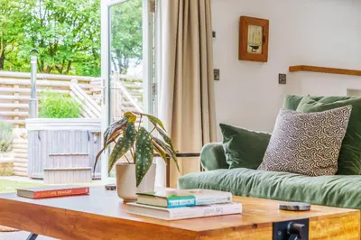 a living room with a green couch and a table with books at The Granary in Camelford