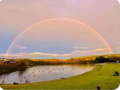 a rainbow over a pond with a group of people at The Beach Retreat in Par