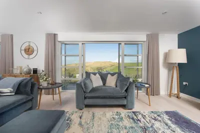 a living room with a couch and a large window at Sandyford, Holywell Bay - Sea Views - Walk to Beach - 2 Pets Allowed - Free Parking and WiFi in Holywell Bay