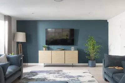 a living room with a tv on a blue wall at Sandyford, Holywell Bay - Sea Views - Walk to Beach - 2 Pets Allowed - Free Parking and WiFi in Holywell Bay