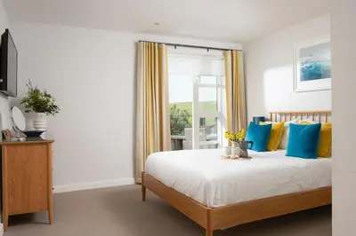 a bedroom with a bed with blue and yellow pillows at Sandyford, Holywell Bay - Sea Views - Walk to Beach - 2 Pets Allowed - Free Parking and WiFi in Holywell Bay