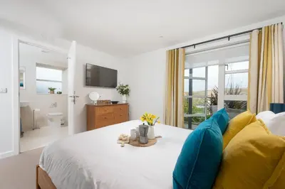 a bedroom with a large bed and a bathroom at Sandyford, Holywell Bay - Sea Views - Walk to Beach - 2 Pets Allowed - Free Parking and WiFi in Holywell Bay