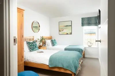 a bedroom with two beds and a window at Sandyford, Holywell Bay - Sea Views - Walk to Beach - 2 Pets Allowed - Free Parking and WiFi in Holywell Bay