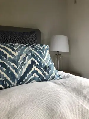 a bed with a blue and white pillow and a lamp at The Hayloft - New Dog friendly with garden and parking in Port Isaac