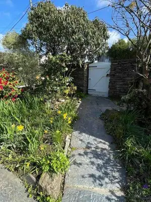 a garden with flowers and a white garage at The Hayloft - New Dog friendly with garden and parking in Port Isaac