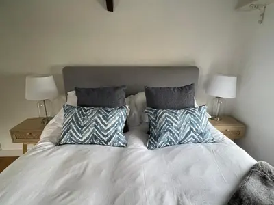 a bed with two pillows on it with two tables at The Hayloft - New Dog friendly with garden and parking in Port Isaac