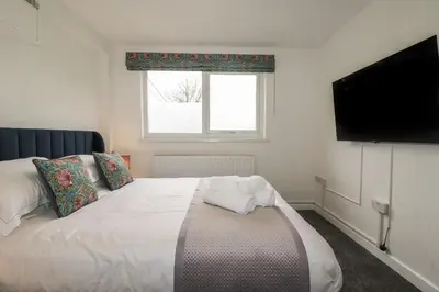a bedroom with a white bed with a flat screen tv at The Retreat in Bodmin