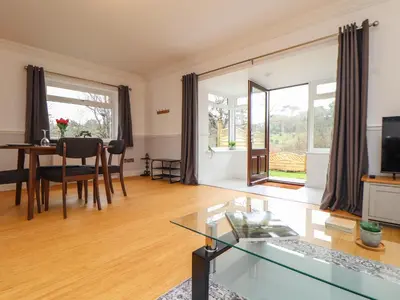 a living room with a glass table and a dining room at Swans Nest in Falmouth
