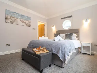 a bedroom with a large bed and a chair at Swans Nest in Falmouth