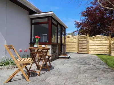 a patio with a wooden fence and a table and a chair at Swans Nest in Falmouth