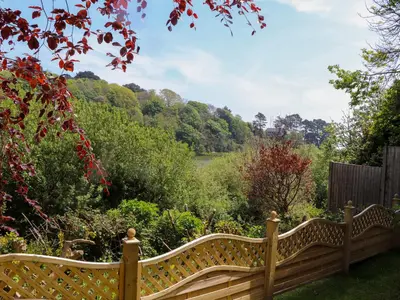 a wooden bench in the middle of a garden at Swans Nest in Falmouth