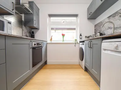 a kitchen with gray cabinets and a window at Swans Nest in Falmouth