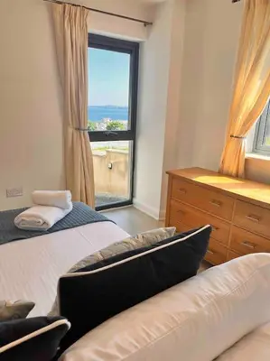 a bedroom with two beds and a window with a view at 2Bed with Pool & Sea View Apartment in Newquay