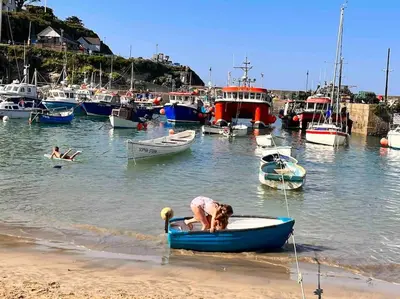 a person in a small boat in the water at 2Bed with Pool & Sea View Apartment in Newquay