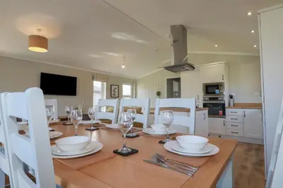 a dining room with a wooden table and white chairs at 4 Meadow Retreat in Liskeard