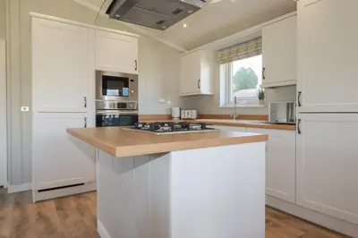 a kitchen with white cabinets and a counter top at 4 Meadow Retreat in Liskeard