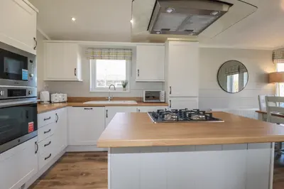 a kitchen with white cabinets and a wooden counter top at 4 Meadow Retreat in Liskeard