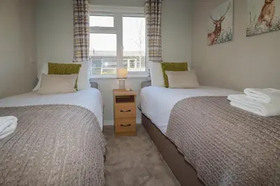two beds in a small room with a window at 4 Meadow Retreat in Liskeard