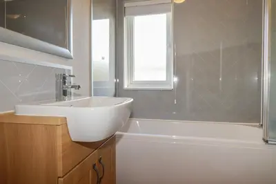 a bathroom with a white sink and a tub and a window at 4 Meadow Retreat in Liskeard