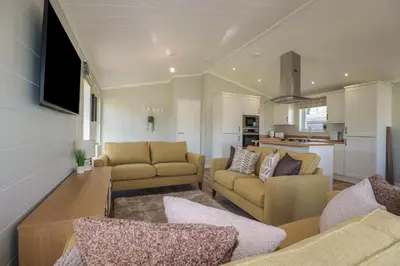 a living room with two couches and a kitchen at 4 Meadow Retreat in Liskeard